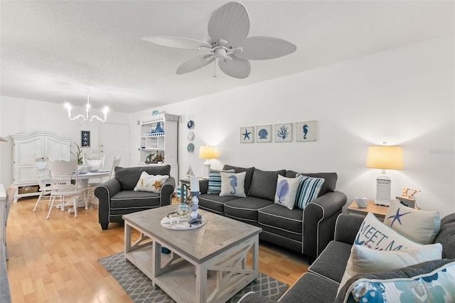 living room featuring hardwood / wood-style flooring, ceiling fan with notable chandelier, and a textured ceiling