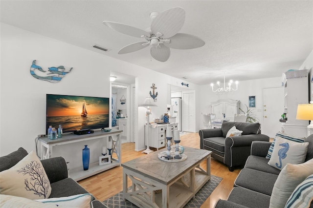 living room featuring a textured ceiling, ceiling fan with notable chandelier, and light wood-type flooring