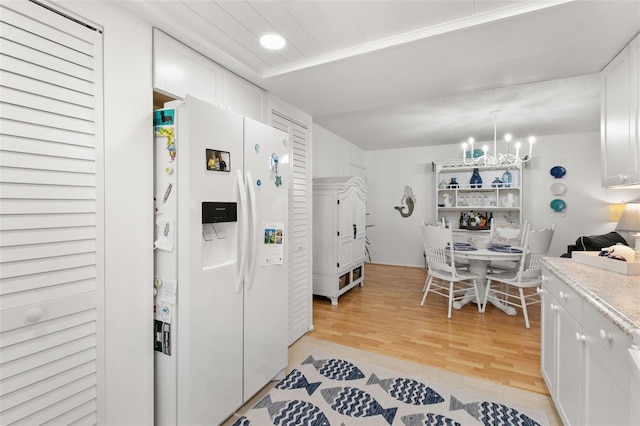 kitchen with white cabinets, a chandelier, white refrigerator with ice dispenser, and light wood-type flooring