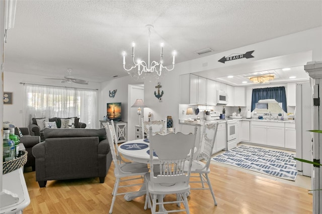 dining room with a textured ceiling, ceiling fan with notable chandelier, light hardwood / wood-style floors, and sink