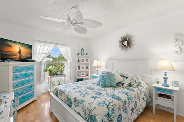 bedroom with light wood-type flooring, a textured ceiling, and ceiling fan