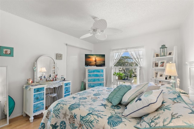 bedroom with ceiling fan, light hardwood / wood-style floors, and a textured ceiling