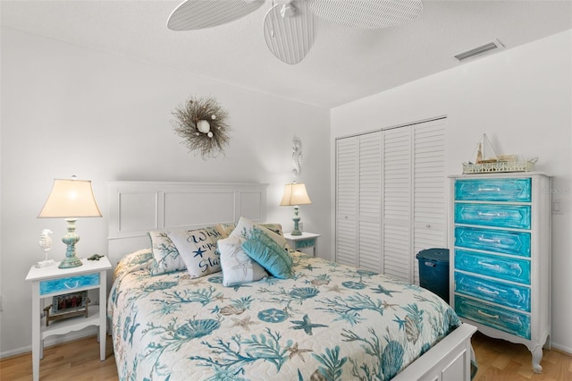 bedroom with a textured ceiling, ceiling fan, light hardwood / wood-style flooring, and a closet