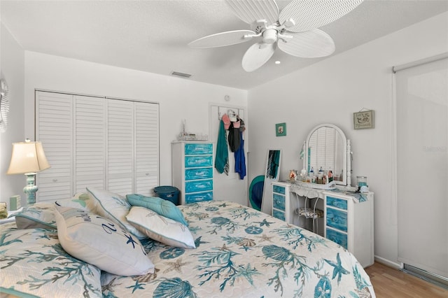 bedroom featuring ceiling fan, a closet, light hardwood / wood-style floors, and a textured ceiling