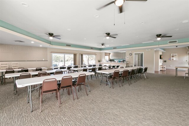 dining area with ceiling fan and light colored carpet