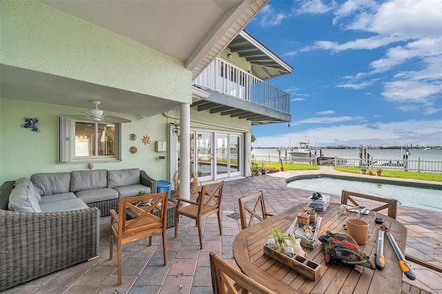 view of patio featuring a balcony, a fenced in pool, a water view, and an outdoor living space