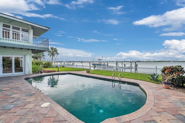 view of swimming pool with a yard, a patio, and a water view