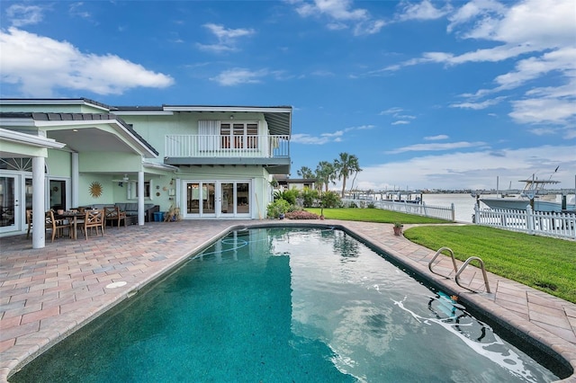 rear view of property featuring a balcony, a yard, a water view, and a patio area