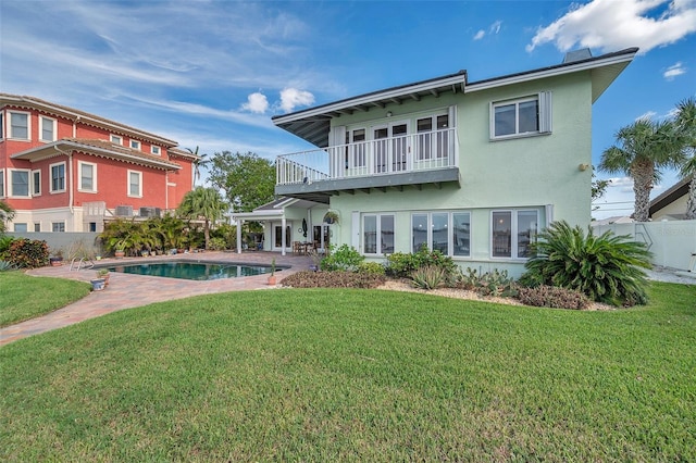 back of house with a patio, a balcony, a fenced in pool, and a yard