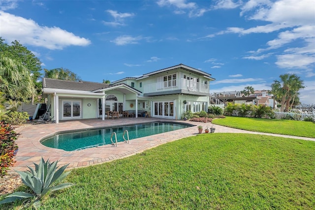 back of house with a balcony, a fenced in pool, a yard, a patio area, and french doors