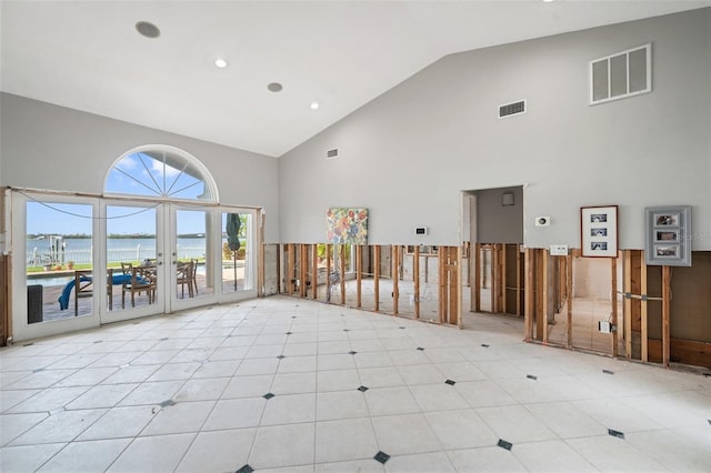 unfurnished room with french doors, high vaulted ceiling, and a water view