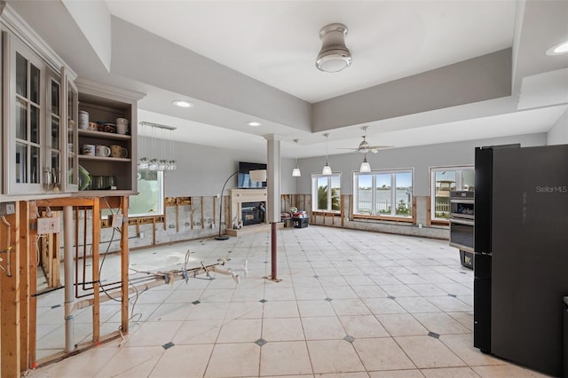 kitchen featuring light tile patterned flooring, ceiling fan, decorative light fixtures, decorative columns, and black refrigerator