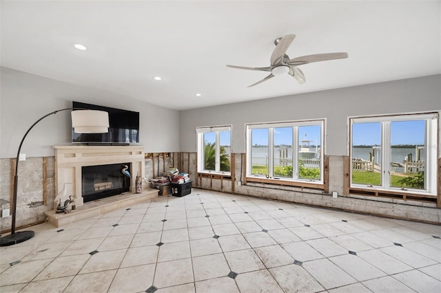 unfurnished living room with ceiling fan and a water view