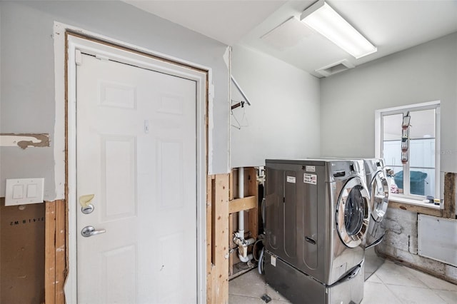 laundry area with washing machine and dryer and light tile patterned floors