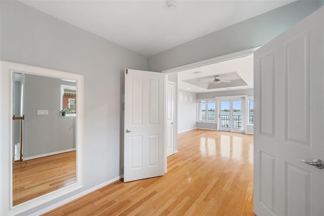 interior space with hardwood / wood-style flooring, ceiling fan, and a tray ceiling