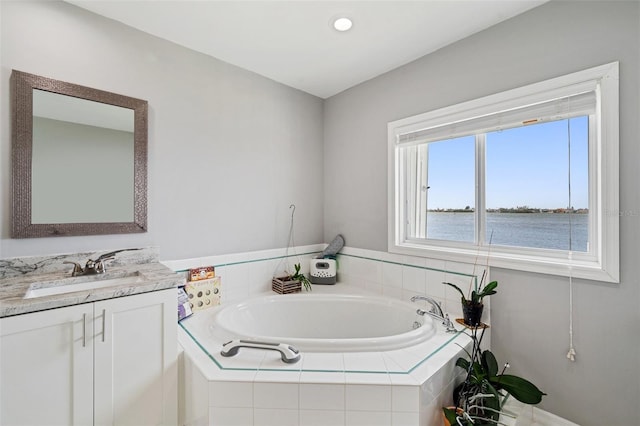 bathroom featuring vanity, a water view, and tiled tub