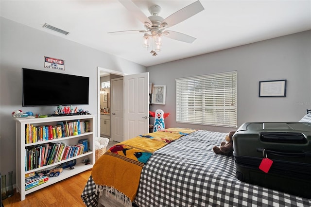 bedroom featuring hardwood / wood-style floors, ensuite bathroom, and ceiling fan