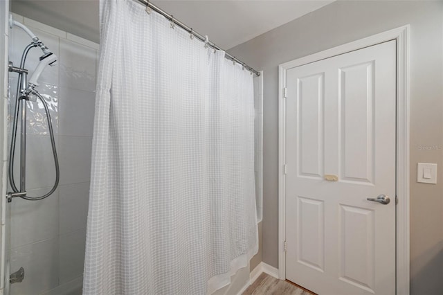 bathroom featuring wood-type flooring and shower / bath combo with shower curtain