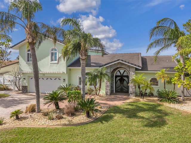 mediterranean / spanish house with french doors, a garage, and a front lawn