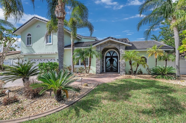 mediterranean / spanish home featuring a garage, french doors, and a front lawn