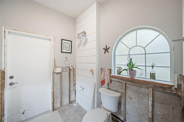 bathroom with toilet and tile walls