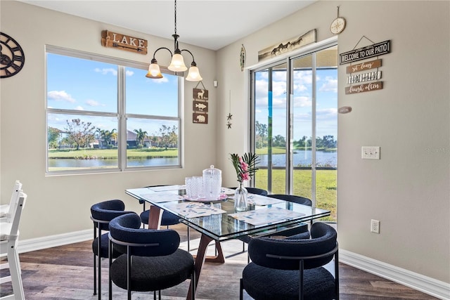 dining space featuring a chandelier, dark hardwood / wood-style flooring, a water view, and a healthy amount of sunlight