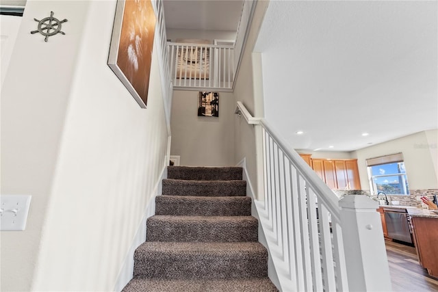 stairs featuring wood-type flooring and sink