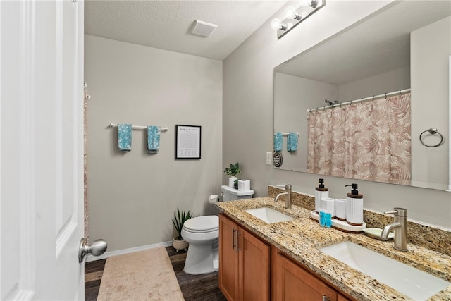 bathroom with vanity, hardwood / wood-style floors, a textured ceiling, and toilet