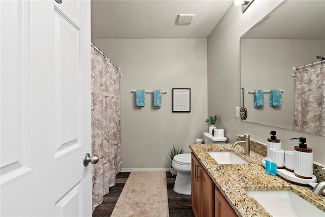 bathroom with hardwood / wood-style flooring, vanity, toilet, and a textured ceiling