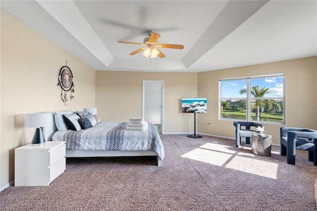 carpeted bedroom with a tray ceiling and ceiling fan