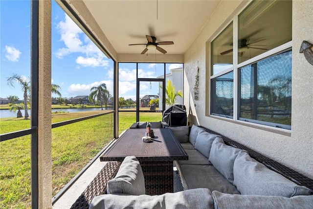 sunroom featuring ceiling fan and a water view