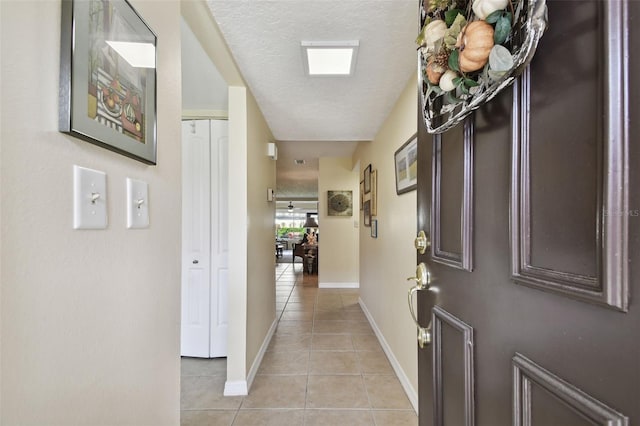 corridor with a textured ceiling and light tile patterned flooring