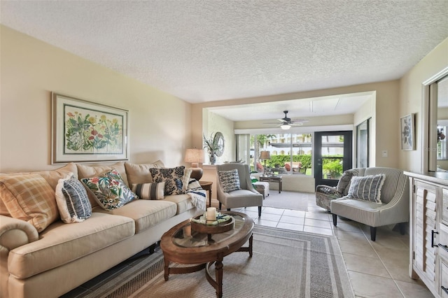 living room featuring ceiling fan, light tile patterned flooring, and a textured ceiling