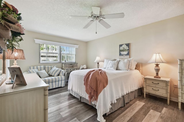 bedroom with a textured ceiling, ceiling fan, and dark wood-type flooring