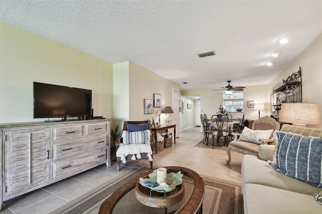 tiled living room with ceiling fan and a textured ceiling