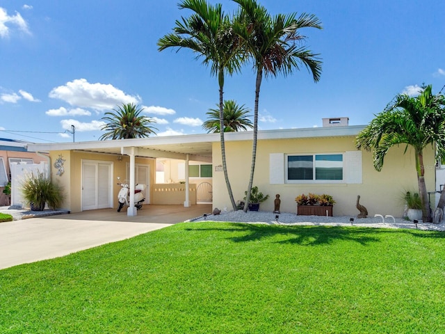 16126 4th St E, Redington Beach, FL 33708 - view of front of home with stucco siding, an attached carport, a front lawn, and concrete driveway