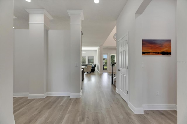 corridor featuring ornate columns, a textured ceiling, and light wood-type flooring