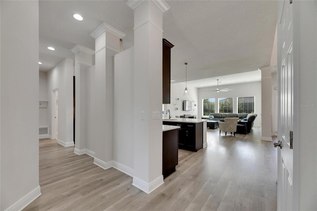 kitchen with ornate columns, ceiling fan, sink, light hardwood / wood-style flooring, and decorative light fixtures