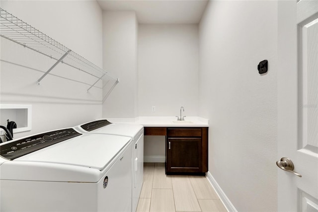 clothes washing area with washer and clothes dryer, cabinets, and sink