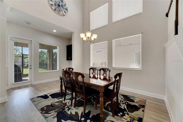 dining room with light hardwood / wood-style floors, a high ceiling, and a notable chandelier