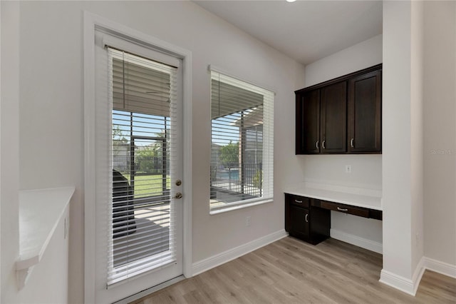 doorway to outside featuring light wood-type flooring and built in desk