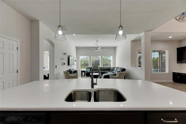 kitchen featuring sink, pendant lighting, a textured ceiling, a center island with sink, and hardwood / wood-style flooring