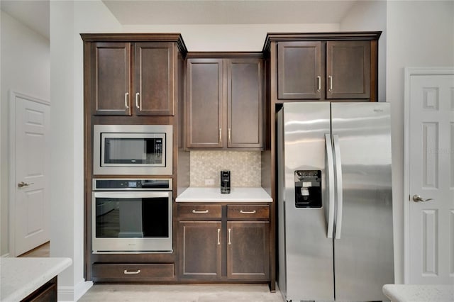 kitchen with appliances with stainless steel finishes, dark brown cabinetry, and backsplash