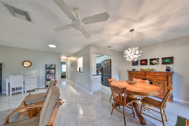 dining area with ceiling fan with notable chandelier and a textured ceiling