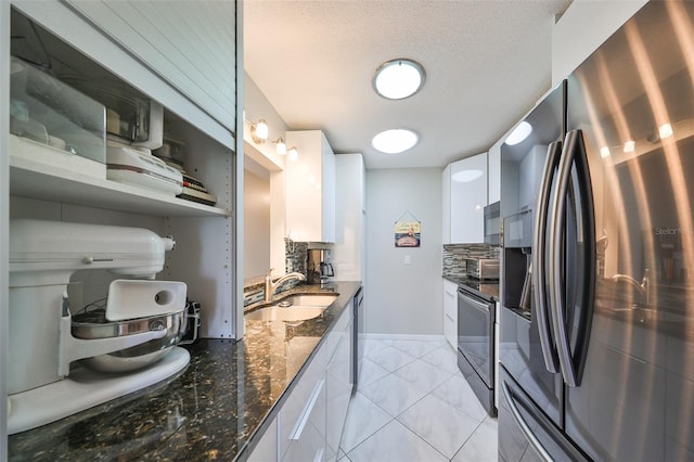 kitchen featuring dark stone counters, white cabinetry, appliances with stainless steel finishes, decorative backsplash, and sink