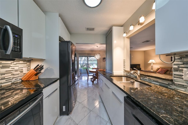 kitchen with white cabinets, black appliances, dark stone counters, and tasteful backsplash