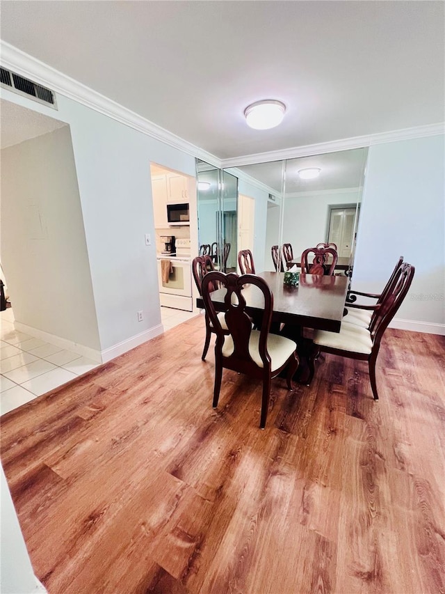 dining space with ornamental molding and light hardwood / wood-style floors