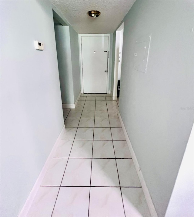 hall with light tile patterned floors and a textured ceiling