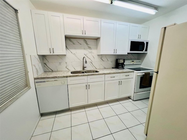 kitchen with white appliances, white cabinetry, sink, and tasteful backsplash