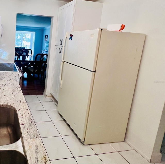 kitchen with white cabinets, light stone counters, crown molding, white appliances, and light tile patterned floors